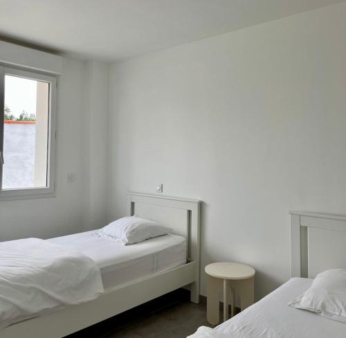 a white bedroom with two beds and a window at EKR Résidence - Terrasse Privée 2 in Carbon-Blanc
