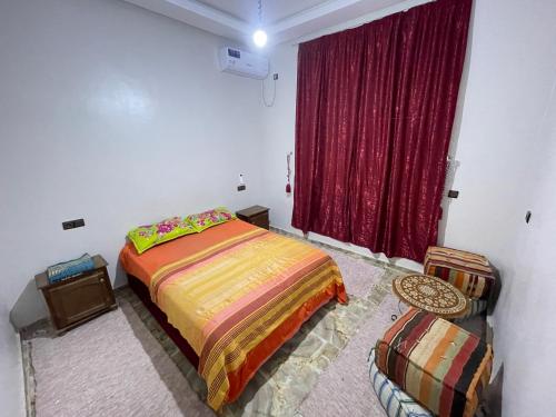 a bedroom with a bed and a red curtain at Maison-Lala Takerkoust et agafay in Lalla Takerkoust