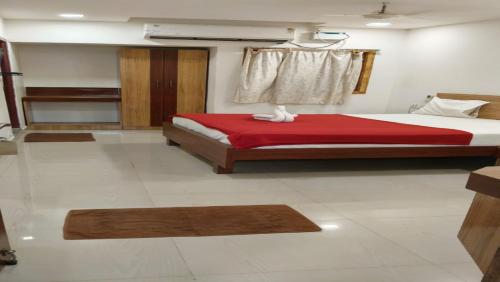 a bedroom with a large bed with a red blanket at Raya's Inn in Kumbakonam
