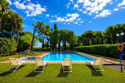 a swimming pool with chairs and trees in a yard at Villa COLONIAL in Vilaseca de Solcina