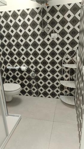 a bathroom with a toilet and a black and white wall at Dimora L&A in Portocannone