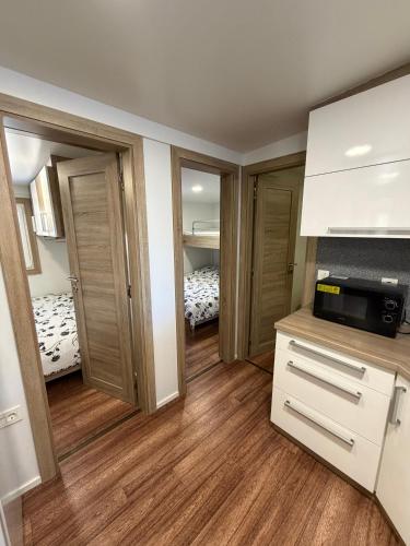 a room with two beds and a kitchen with wooden floors at MOBILE HOME Nikol in Pirovac