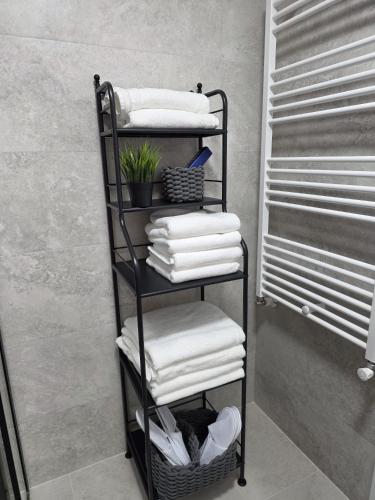 a black towel rack with white towels in a bathroom at Colins Premium Apartments in Giurgiu