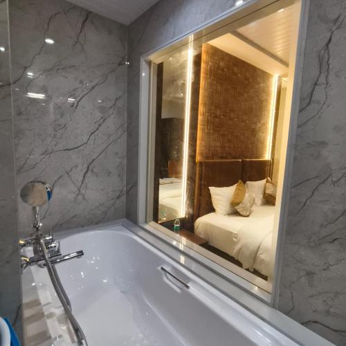 a bathroom with a tub with a bedroom in the mirror at Mi Residency Lodging & Boarding in Thane