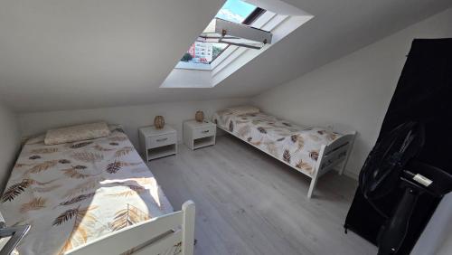 a attic room with two beds and a window at Square View Apartment Center Niksic in Nikšić