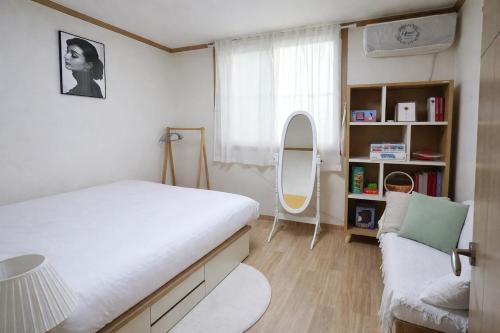 a bedroom with a bed and a couch and a mirror at MAMA Alice in Seoul