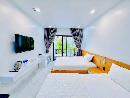 a bedroom with two beds and a flat screen tv at Bay Homestay in Cam Lâm