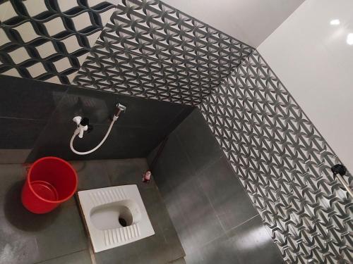 a bathroom with a toilet and a red bucket at VBH Tourist Homestay in Guruvāyūr