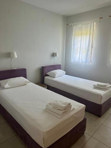 two beds in a room with white walls and a window at Glikis ear apartments in Gliki