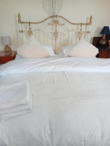 a white bed with white sheets and pillows at Owls Roost in Stowmarket