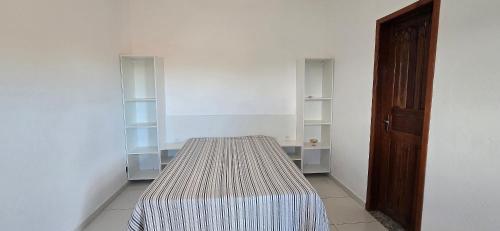 a room with a bed in a room with shelves at Casa Temporada Lua Nova in Guriri