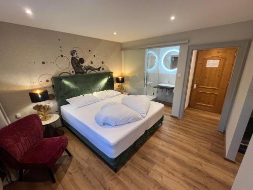 a bedroom with a large white bed and a chair at Landhotel Lindenhof in Feld am See