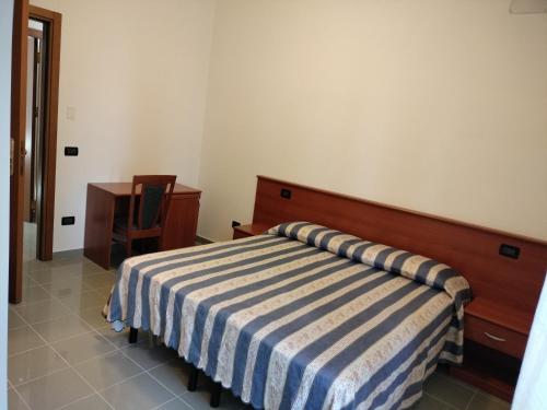 a bedroom with a bed with a blue and white striped blanket at Oasi della Divina Volontà in San Giovanni Rotondo