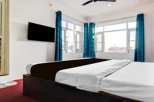 a bedroom with a large bed with blue curtains at Hotel O Wave Inn in Srinagar