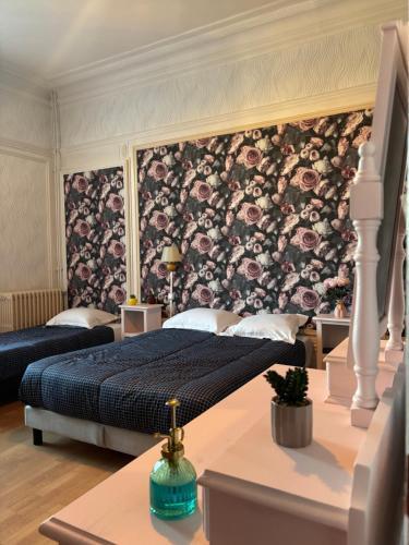 a bedroom with two beds and a floral wallpaper at Hotel du chateau blanc in Saint-Aubin-lès-Elbeuf