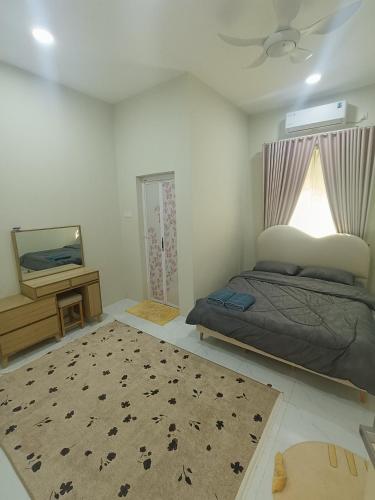 a bedroom with a bed and a tv and a rug at Serai Homestay in Dungun