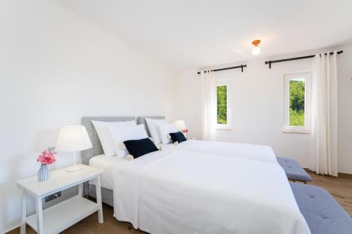 a white bedroom with a large white bed and a couch at Apartment Ana with private pool in Otok