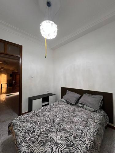 a bedroom with a bed with a black and white blanket at Residence el baraka in Bou Zadjar