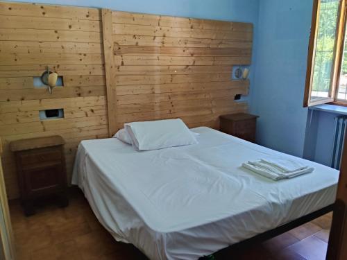 ein Schlafzimmer mit einem weißen Bett und einer Holzwand in der Unterkunft la sequoia in Castagneto Po
