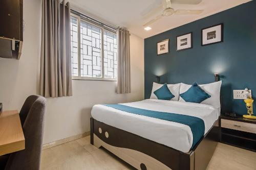 a bedroom with a bed with blue walls and a window at Hotel O Nirsukh Palace in Navi Mumbai