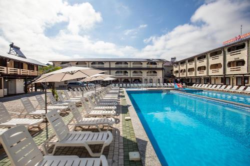 a swimming pool with lounge chairs and an umbrella at Золотий Павлін in Solotvyno