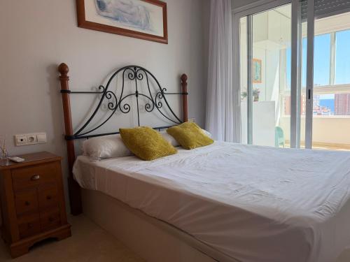 a bedroom with a bed with two yellow pillows at Gemeleos22 in Benidorm