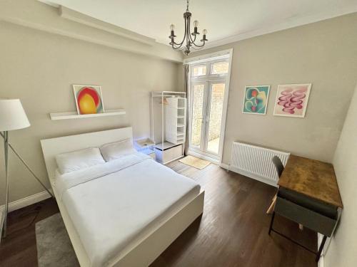 a bedroom with a bed and a desk and a window at Stylish 2BR Flat 3 Mins to Wembley Stadium in London