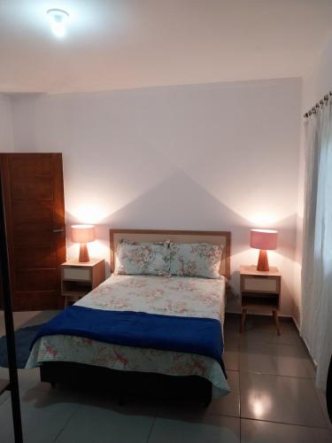 a bedroom with a bed with two lamps on two tables at Casa da matta in Ubatuba