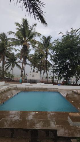a swimming pool with palm trees in the background at Lake N Trails Exotic Glamping in Khālāpur