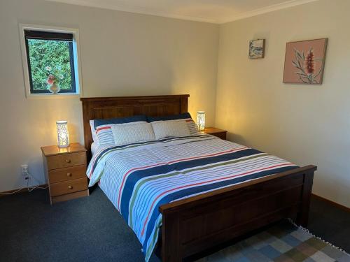 a bedroom with a bed with two night stands and a window at Spacious peaceful apartment in Wellington