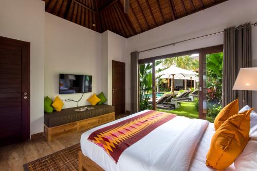 a bedroom with a bed and a tv and a patio at Villa Anam in Seminyak