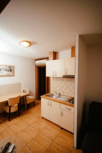 a kitchen with white cabinets and a table and a dining room at Prenočište M & S in Valpovo
