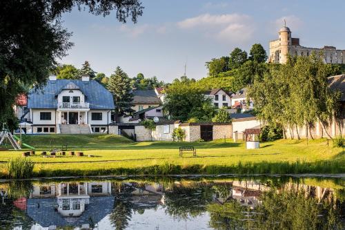 a house on a hill next to a body of water at Dwór Meluzyna in Janowiec