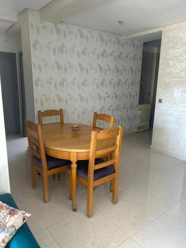 a wooden table with two chairs and a bowl on it at Appart 5min plage, plein centre in Sidi Rahal