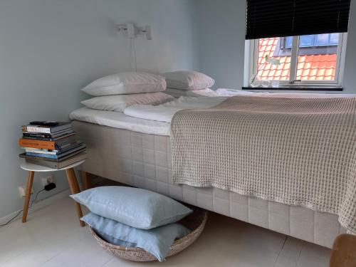 a bed with pillows on it next to a window at Tiny flat - in medieval Ystad in Ystad