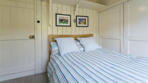 a bed in a bedroom with two pictures on the wall at Beach Bungalow in Nefyn