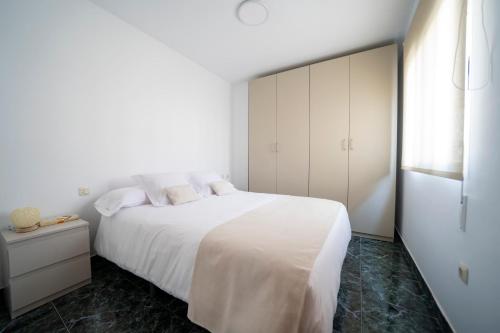 a white bedroom with a large white bed and a window at Casa El Pilar in Serón