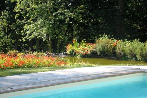 a swimming pool in a garden with flowers at MAISON d HOTES in May-sur-Orne