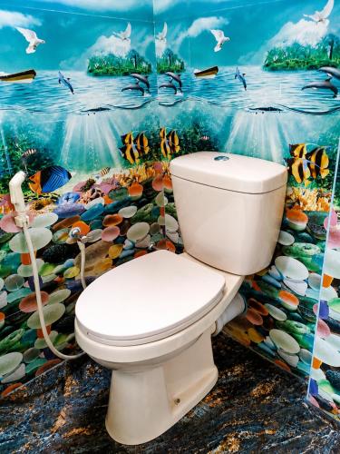 a bathroom with a toilet in front of a painting at Silver Tips Villa in Ella