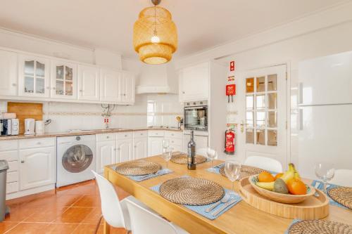 a kitchen with a wooden table and white cabinets at Baleal Happiness Surf House in Baleal