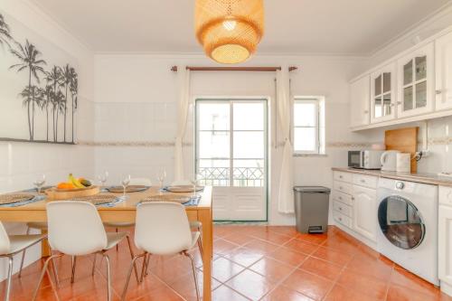 a kitchen with a table and white cabinets and a table and chairs at Baleal Happiness Surf House in Baleal