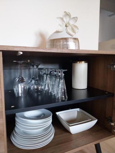 a shelf with plates and glassware in a kitchen at L'appartement de Sigrid in Pézenas