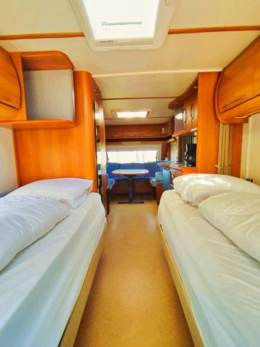 three beds in a small room with a table at The Sûre & Simple Caravan in Houschthauser