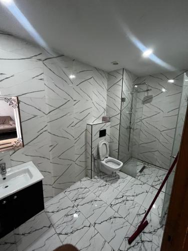 a white bathroom with a toilet and a sink at Sweet home in Ariana