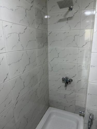 a white tiled shower with a sink in a bathroom at Studio 3rd Floor Blumar one bedroom in El Alamein