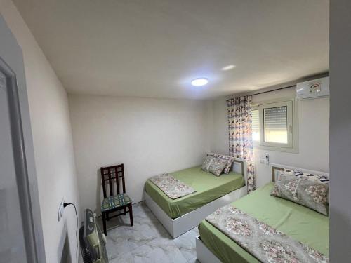 a small bedroom with two beds and a chair at Studio 3rd Floor Blumar one bedroom in El Alamein