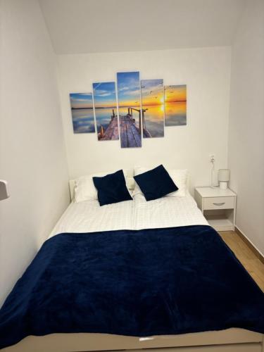 a bedroom with a bed with four paintings on the wall at Tęczowe Lato in Sarbinowo