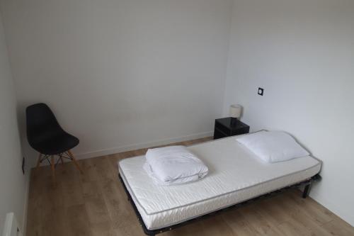a bed with two pillows and a chair in a room at Ty Le Gall in Plouescat