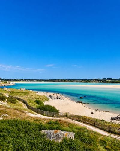 a view of a beach with blue water and a fence at Ty Le Gall in Plouescat