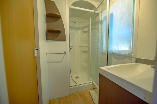 a white bathroom with a shower and a sink at Manoir le Mingreaud Bungalows in Sainte-Gemme-la-Plaine